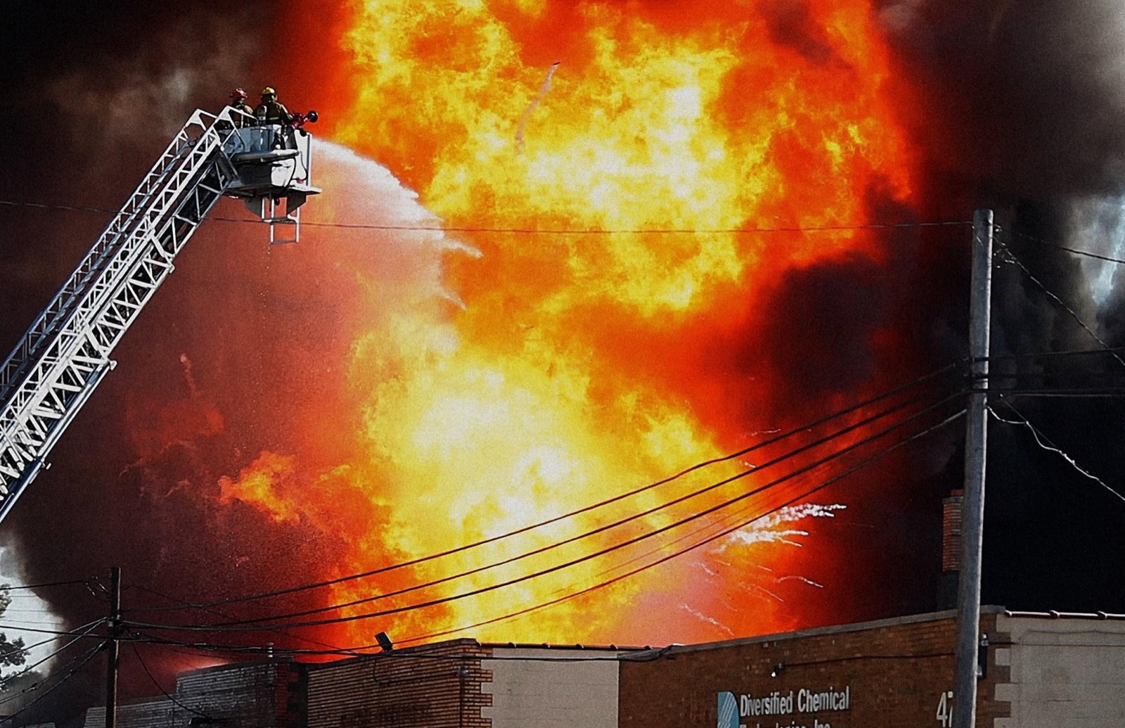 Firefighters on an aerial ladder spraying water into a massive fire during BURN